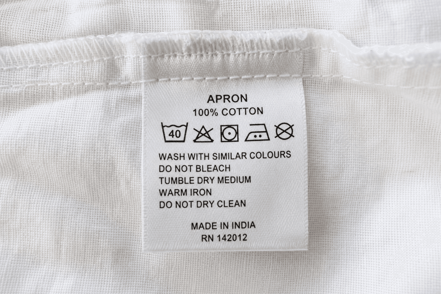 A sewn-in care label with washing symbols inside an apron