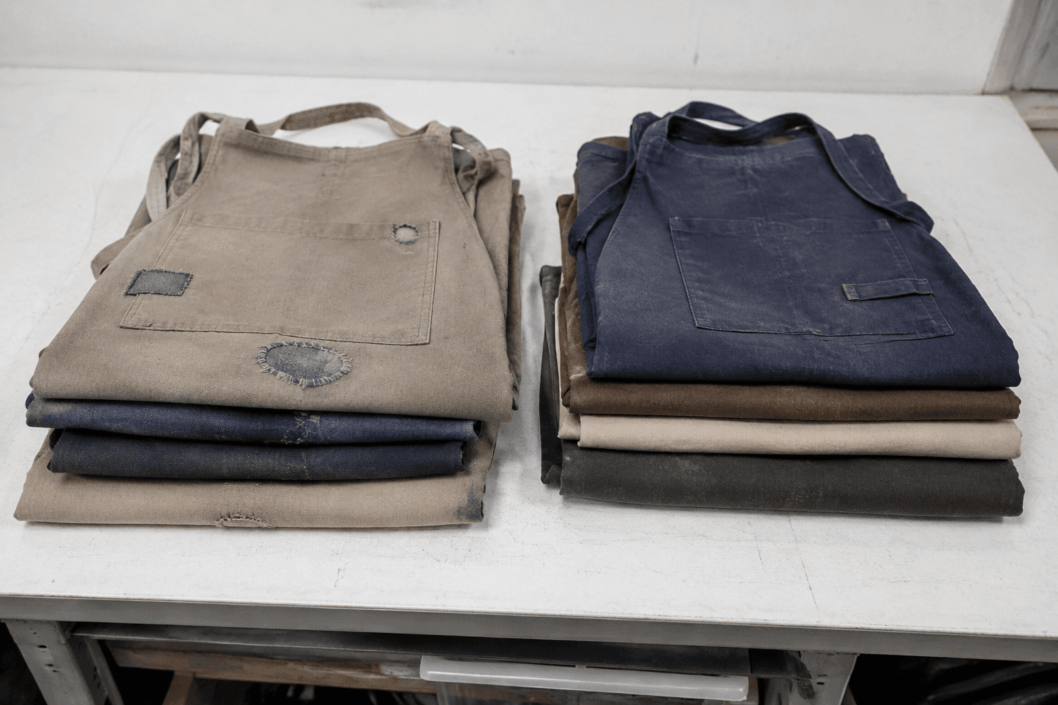 Worn aprons sorted for repair and recycling on a workroom table