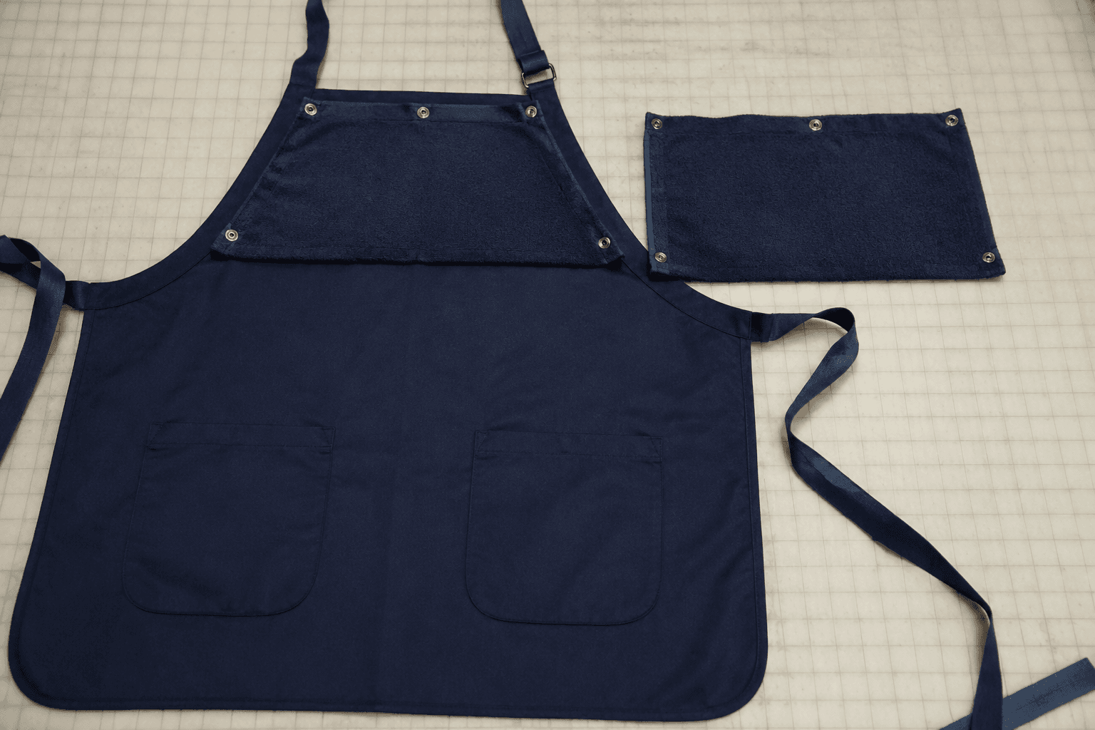 apron sample with snap-off towel attachment and spare towel panel on a cutting table