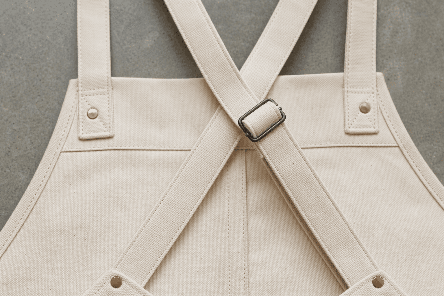 Close-up of apron crossback straps with metal buckles and copper rivets