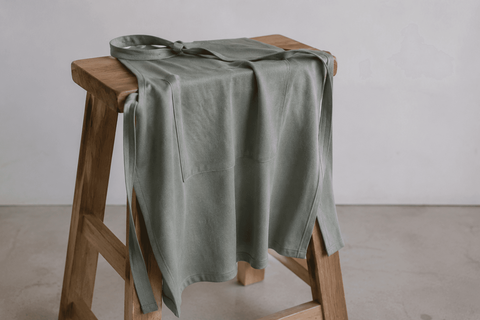 A soft bamboo-blend apron draped over a wooden stool showing fluid drape