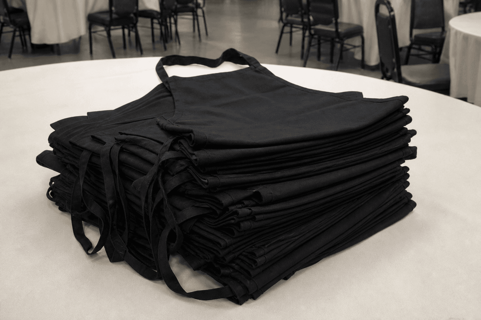 Folded black catering bib aprons stacked for an event