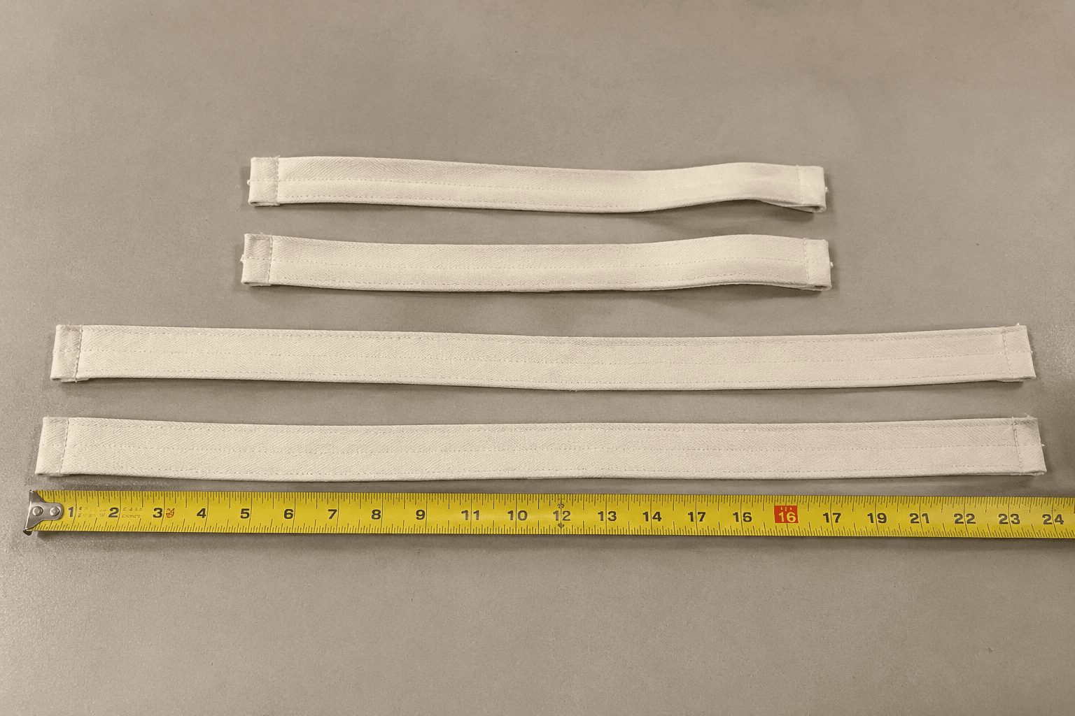 Apron neck and waist straps laid out with a measuring tape