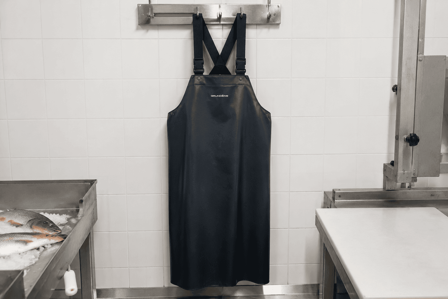 A coated water-resistant fishmonger apron on a stainless steel hook