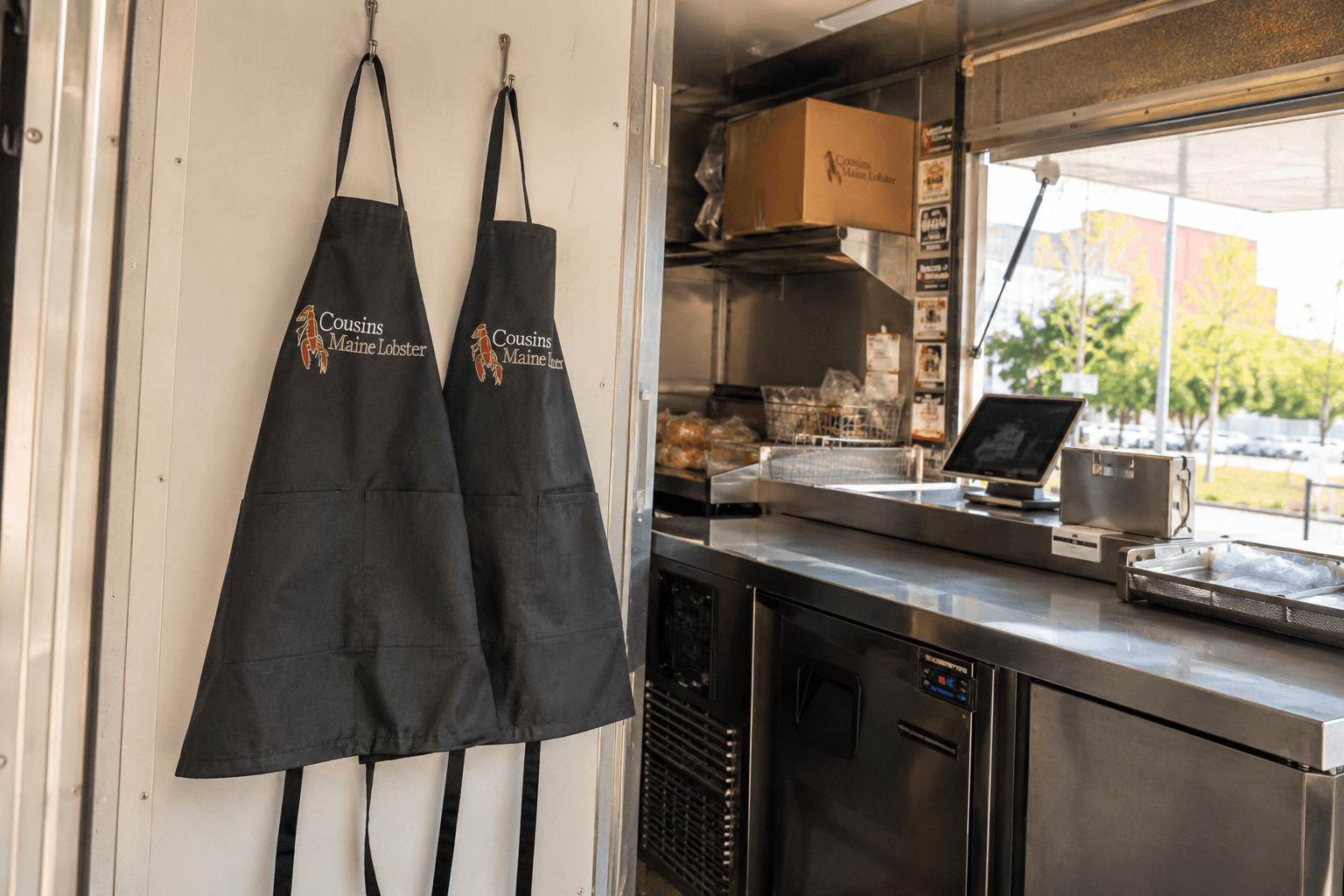 Branded waist aprons hanging inside a food truck service window