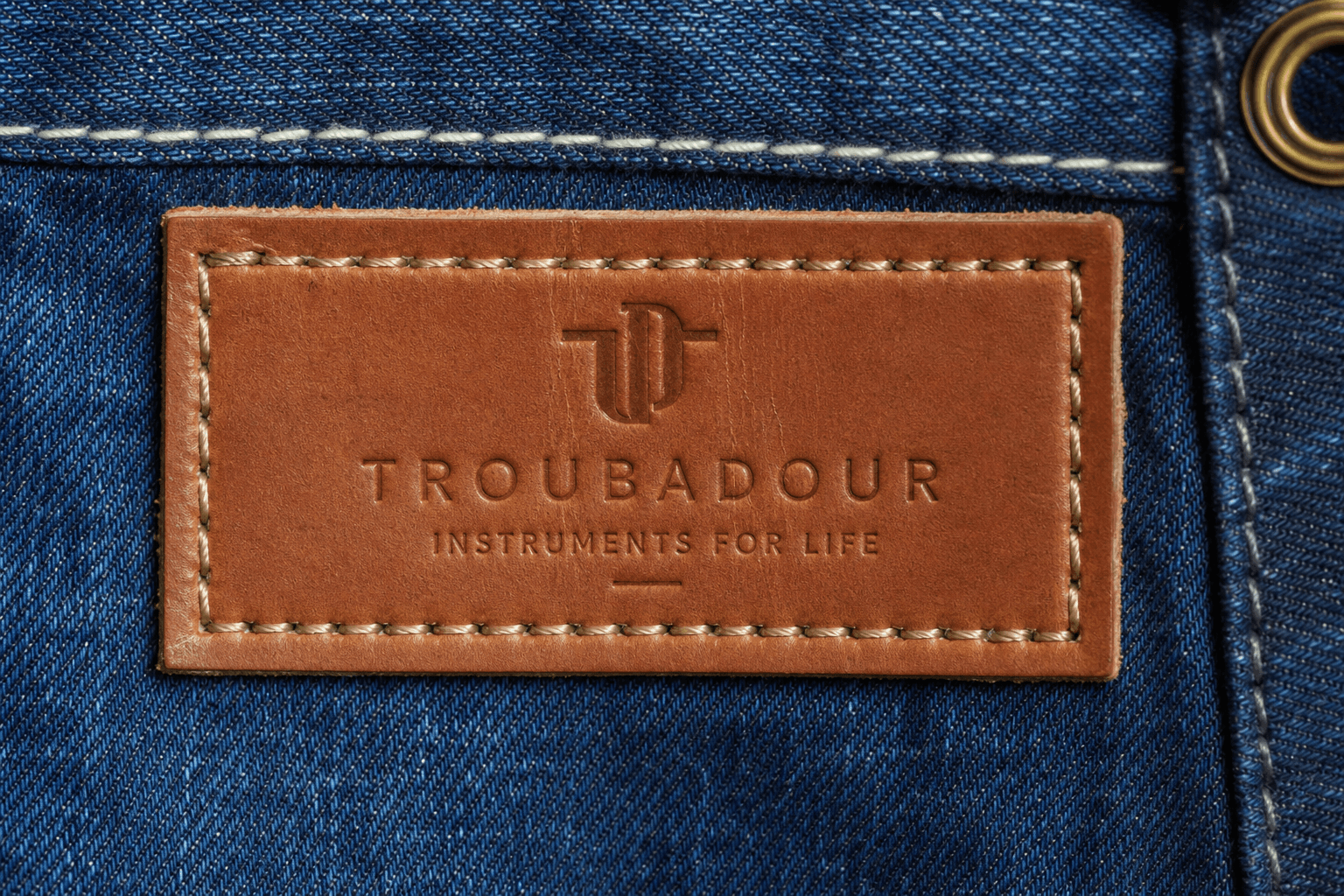 A debossed vegetable-tanned leather patch saddle-stitched onto denim apron fabric