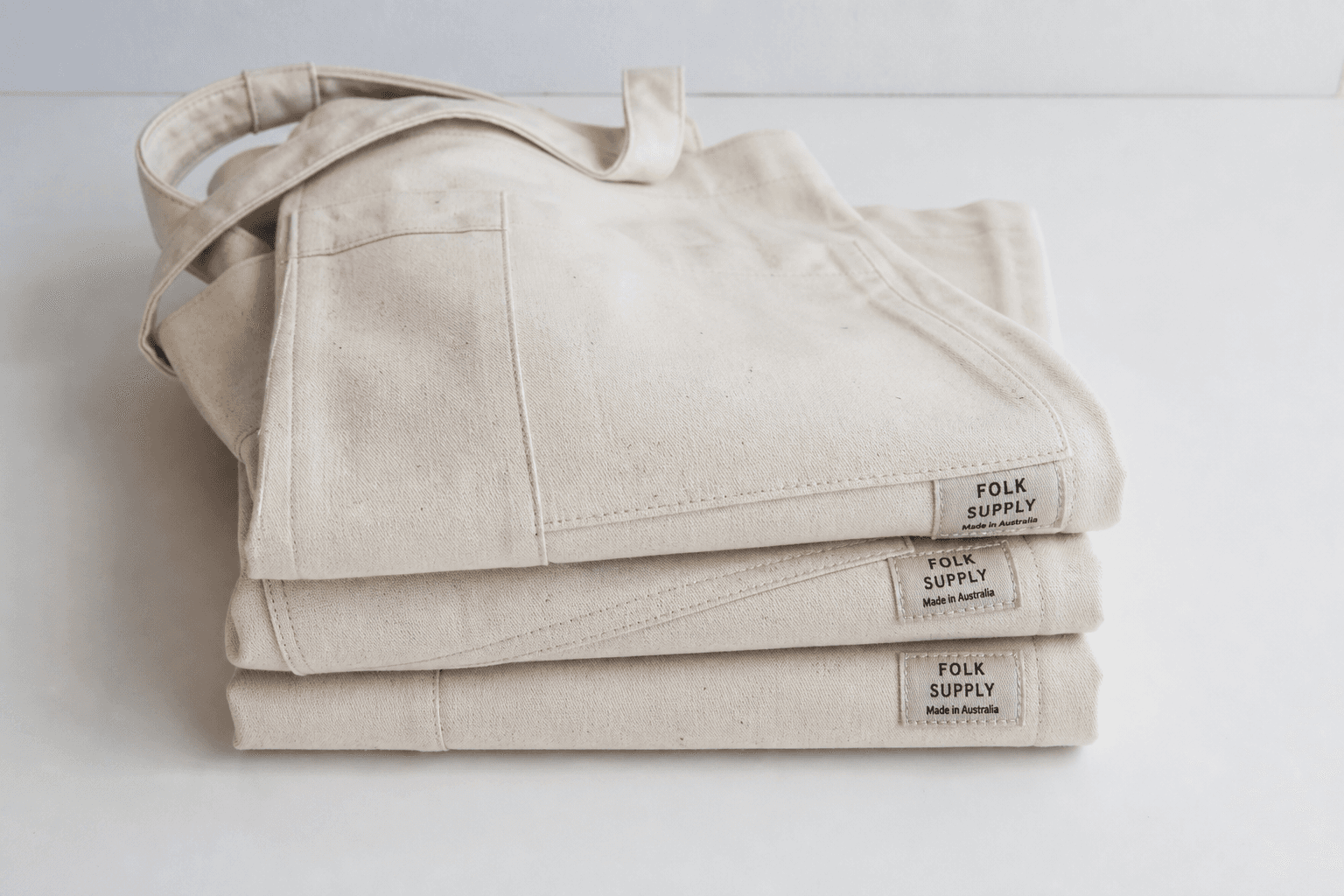 A small batch of folded branded aprons on a startup studio desk