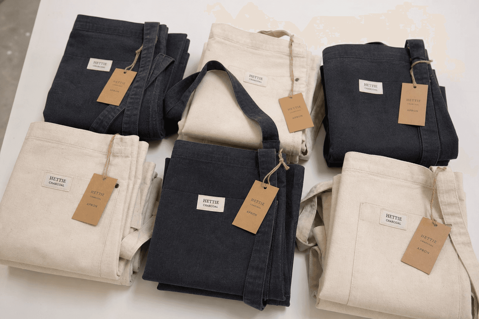 Branded private-label aprons folded with hang tags on a factory table
