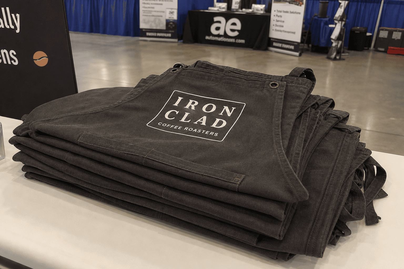 Stacked branded canvas aprons on a conference giveaway table