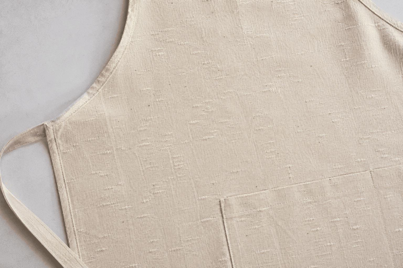 A natural slub-textured cotton apron showing irregular yarn character