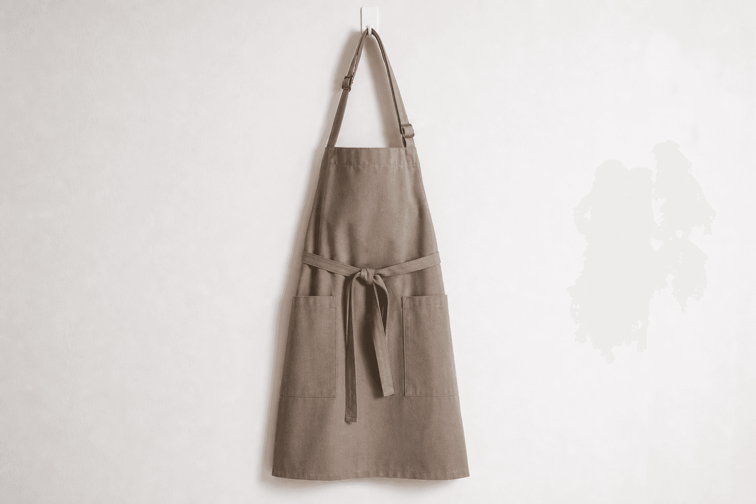 A soft neutral-toned spa apron hanging on a wall hook